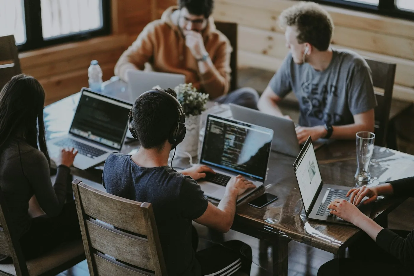 Equipo de trabajo con portátiles alrededor de una mesa de madera en una oficina luminosa